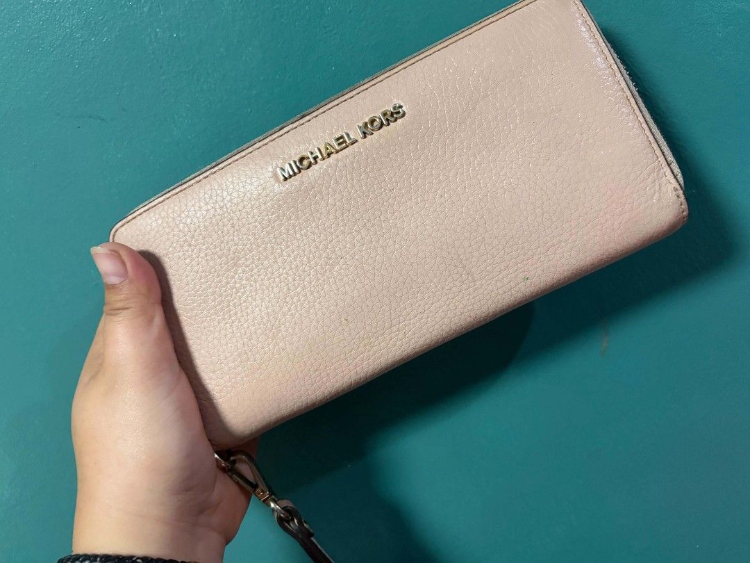 Michael Kors Pink Leather Zip Around Wallet (Category: Wallets & Card holders) located in General Trias. Submitted by happystorm_b8e70b (Listing ID 1441798556, Image 1). Description: - Michael Kors wallet - Light pink color - Genuine leather material - Zip-around closure - Attached wrist strap - Minor exterior wear (as pictured) - Ample interior space for cards and cash - Ideal for everyday use.
