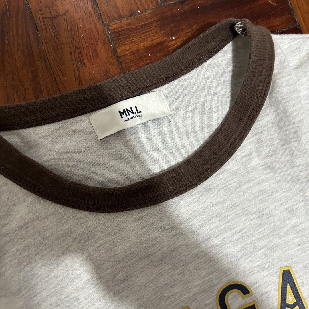 MNL Grey T-shirt with Flower Graphic and "MITIGATE" Text (Category: Tshirts & Polo Shirts ) located in Antipolo. Submitted by wrdrb.co (Listing ID 1441909821, Image 2). Description: - Brand: MNL - Color: Grey - Graphic: Yellow flower with dark blue outline - Text: "MITIGATE" above graphic - Details: Brown ribbed collar and sleeve cuffs - Style: Casual, comfortable - Occasion: Everyday wear.
