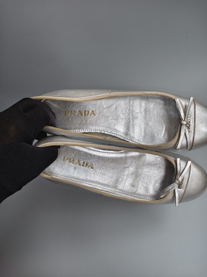 Prada Silver Leather Ballet Flats Bow Detail (Category: Flats & Sandals) located in Binan City. Submitted by eddabrienne (Listing ID 1441855978, Image 1). Description: - Authentic Prada silver leather ballet flats - Size: 35.5 - Features a charming bow detail on the toe - Comfortable slip-on style - Prada logo visible on the insoles - Soles marked with Prada Milano - Made in Italy - Please note: Minor signs of wear on the soles and toe area..