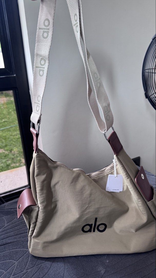 Alo Yoga Beige Nylon Shoulder Bag (Category: Shoulder Bags) located in Batangas. Submitted by kringkring. (Listing ID 1442013279, Image 3). Description: - Brand: Alo Yoga - Color: Beige - Style: Shoulder Bag - Features: Alo logo on front, adjustable branded strap, side pockets, zippered main compartment - Condition: New with original tags attached - Ideal for: Everyday use, gym.