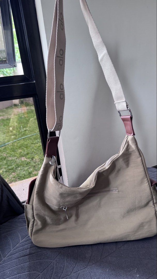 Alo Yoga Beige Nylon Shoulder Bag (Category: Shoulder Bags) located in Batangas. Submitted by kringkring. (Listing ID 1442013279, Image 2). Description: - Brand: Alo Yoga - Color: Beige - Style: Shoulder Bag - Features: Alo logo on front, adjustable branded strap, side pockets, zippered main compartment - Condition: New with original tags attached - Ideal for: Everyday use, gym.