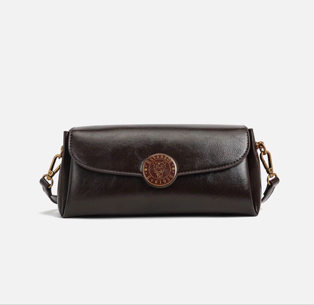 EsVangoh Dark Brown Leather Shoulder Bag (Category: Shoulder Bags) located in Manila. Submitted by pinga_crystal (Listing ID 1442135535, Image 1). Description: - Dark brown leather shoulder bag - Features a circular emblem on the front - Brand name 'EsVangoh' subtly displayed on the back - Comes with a detachable strap for versatile wear - Phone included in photos for accurate size comparison.
