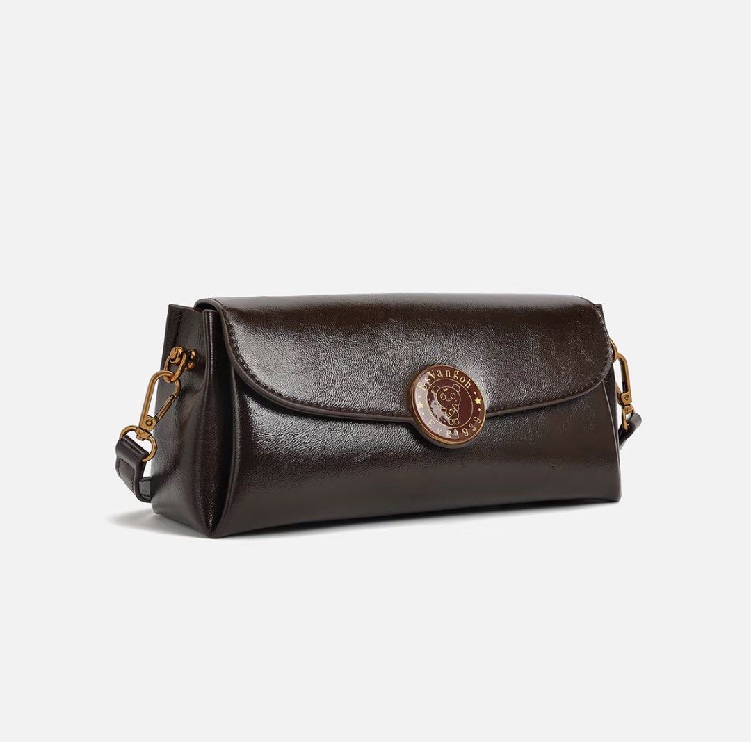 EsVangoh Dark Brown Leather Shoulder Bag (Category: Shoulder Bags) located in Manila. Submitted by pinga_crystal (Listing ID 1442135535, Image 2). Description: - Dark brown leather shoulder bag - Features a circular emblem on the front - Brand name 'EsVangoh' subtly displayed on the back - Comes with a detachable strap for versatile wear - Phone included in photos for accurate size comparison.