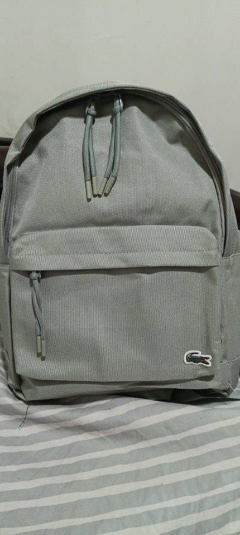 Lacoste Grey Backpack (Category: Backpacks) located in Manila. Submitted by poshcara (Listing ID 1442129156, Image 1). Description: - Grey Lacoste backpack - Front zip pocket and main compartment - Padded straps and back for comfort - Lacoste logo prominently displayed on the front - Clean and simple design - Ideal for everyday use or travel.