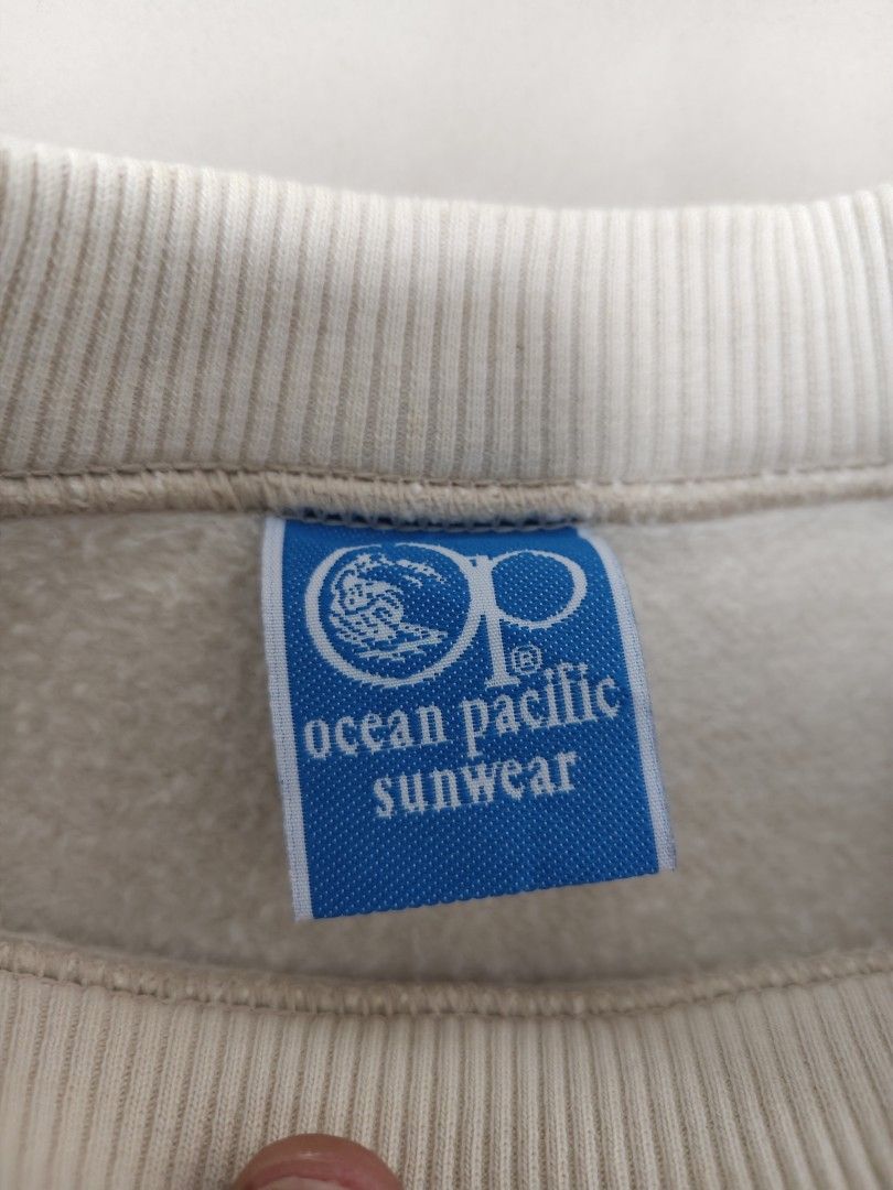 VTG Ocean Pacific OP White Sweatshirt (Category: Coats, Jackets and Outerwear) located in Cavite. Submitted by whew12 (Listing ID 1442009724, Image 3). Description: This item is a vintage Ocean Pacific (OP) crewneck sweatshirt featuring a clean off-white body with contrasting red and blue racing stripes running down the length of both sleeves. - White Ocean Pacific sweatshirt - Features OP logo on back and sleeve - Red and blue stripe details on 