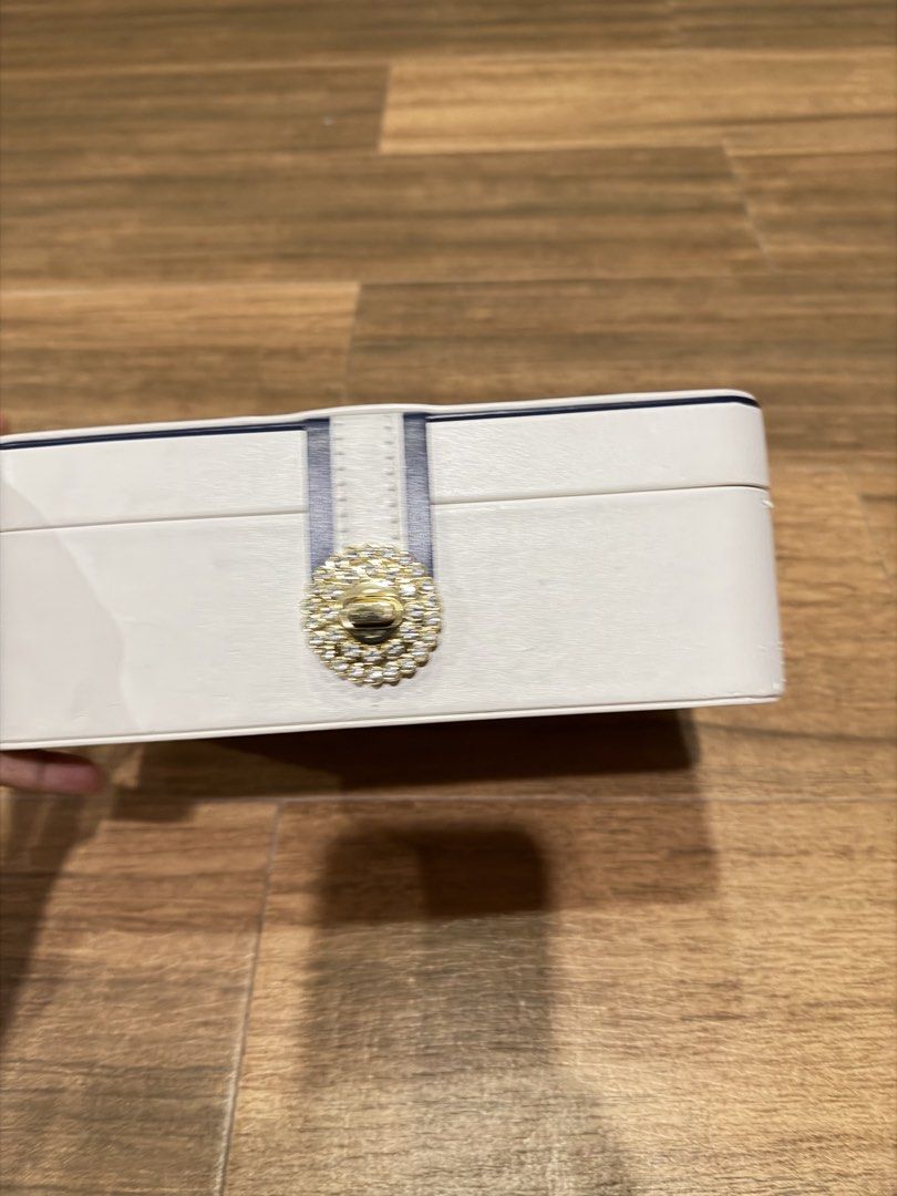 White Jewelry Box with Rhinestone Clasp (Category: Accessory Holder, Box & Organizers) located in Paranaque City. Submitted by lovedstuffby_ang (Listing ID 1442066272, Image 3). Description: - Chic white jewelry box - Features a navy blue and white ribbon detail - Gold-tone clasp adorned with sparkling rhinestones - Ideal for keeping your accessories organized.