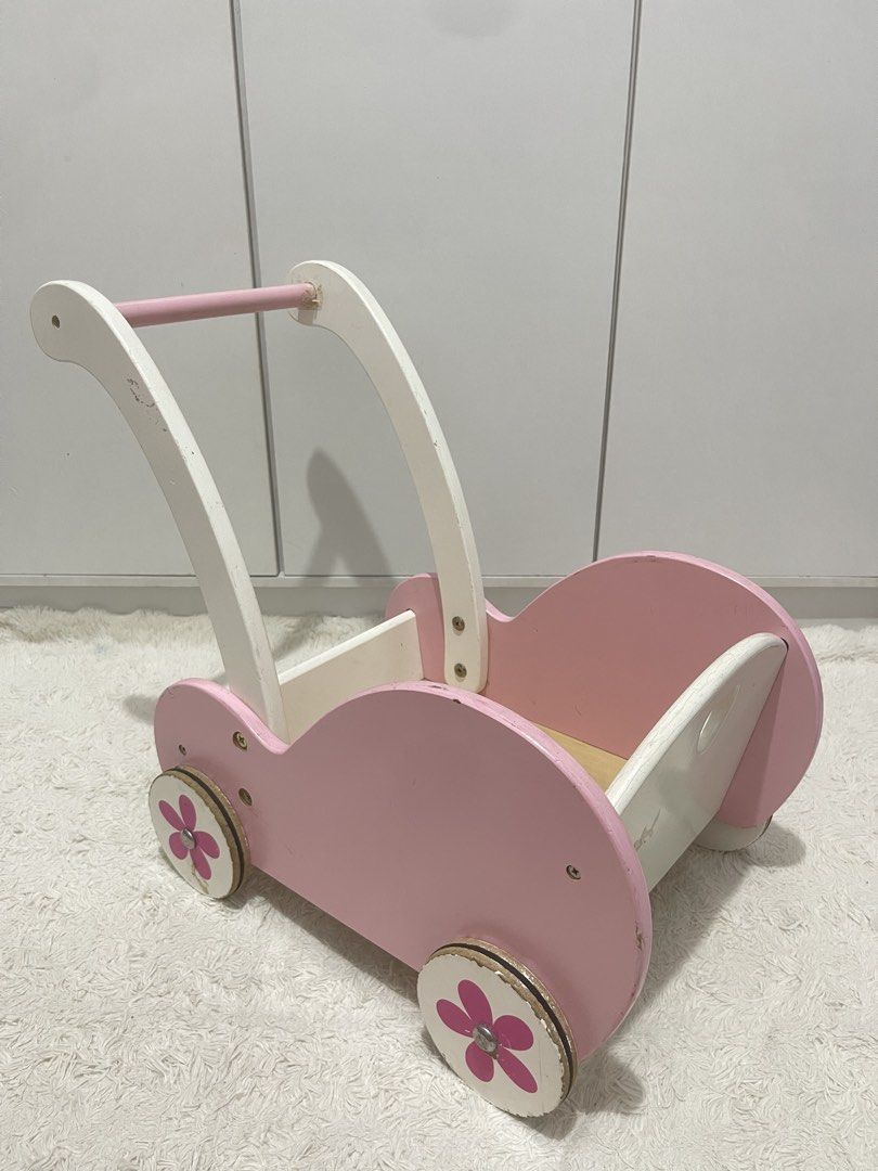Wooden Viga doll stroller/cart (Category: Strollers) located in Manila. Submitted by jassie06 (Listing ID 1442074237, Image 2). Description: NEEDS CLEANING. SUPER NICE 🩷 This wooden Viga doll stroller is designed in pink and white with a charming flower motif on the wheels. Brand and Model: Viga 50176 Baby Doll Stroller Buggy. Key Details: Features include a heart-shaped cutout on the back, shock-absorbing rubber rings on the wheels to protect f