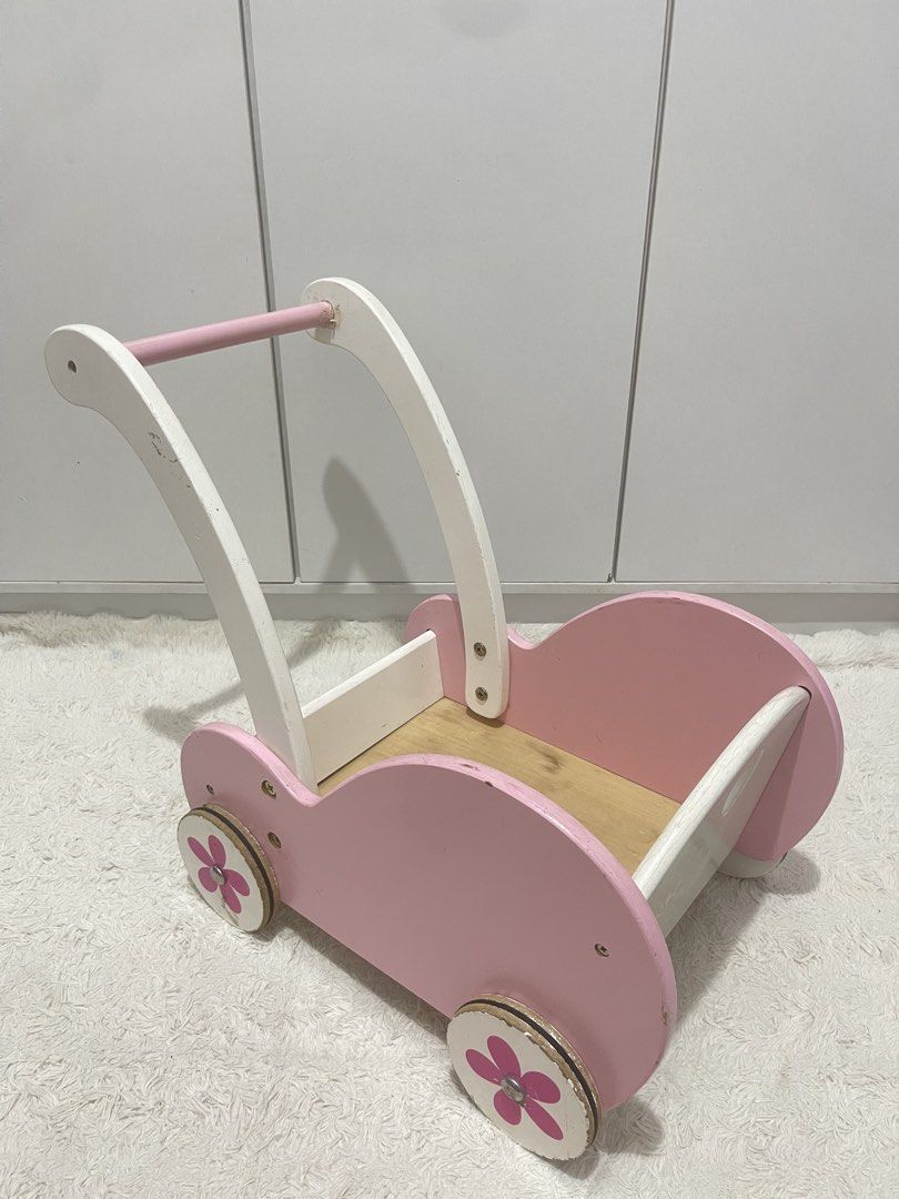 Wooden Viga doll stroller/cart (Category: Strollers) located in Manila. Submitted by jassie06 (Listing ID 1442074237, Image 3). Description: NEEDS CLEANING. SUPER NICE 🩷 This wooden Viga doll stroller is designed in pink and white with a charming flower motif on the wheels. Brand and Model: Viga 50176 Baby Doll Stroller Buggy. Key Details: Features include a heart-shaped cutout on the back, shock-absorbing rubber rings on the wheels to protect f