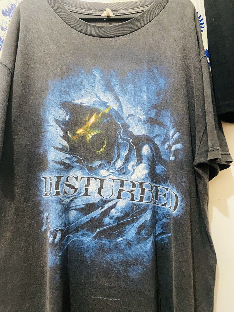 Disturbed Band T-Shirt (Category: Tshirts & Polo Shirts ) located in Manila. Submitted by inyell (Listing ID 1442175617, Image 1). Description: - Vintage Disturbed band t-shirt - Features iconic Disturbed logo and artwork - Dark grey, faded wash - Classic piece for any fan's collection.