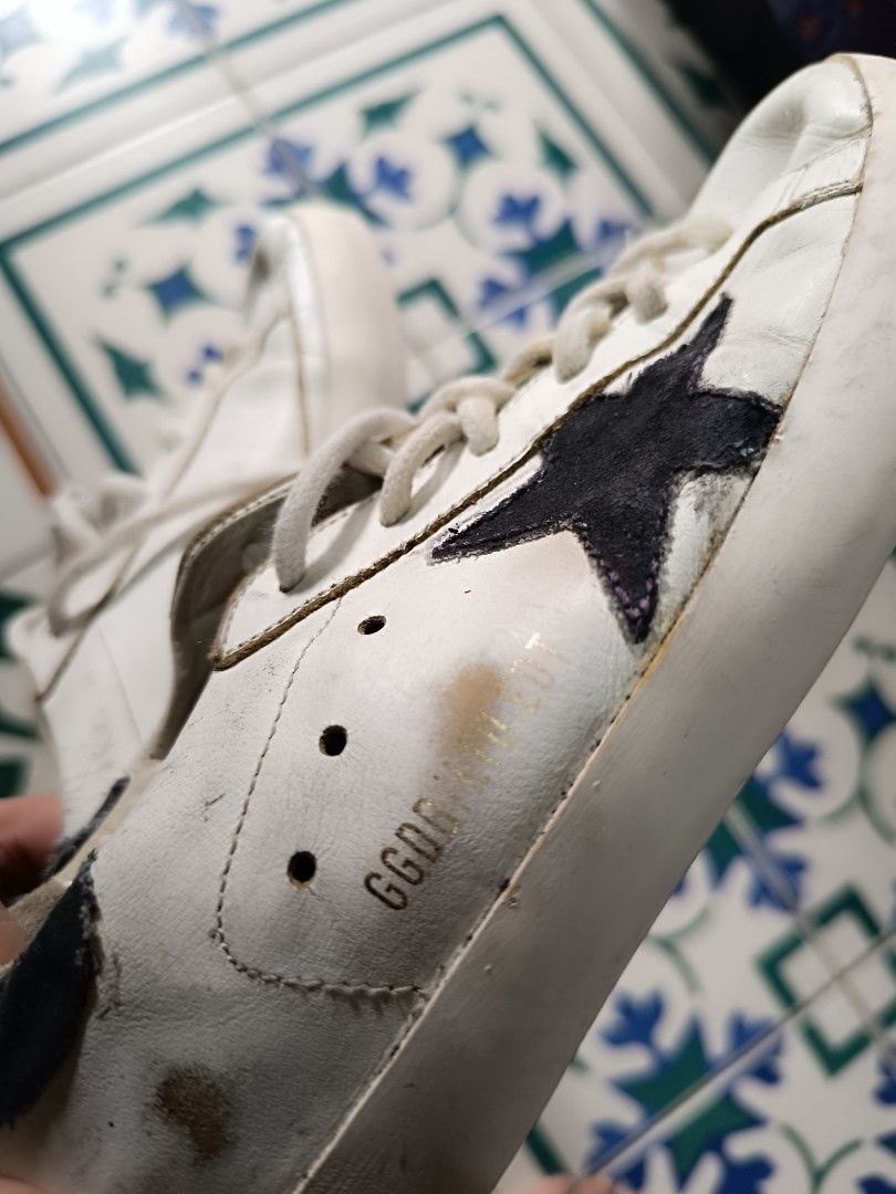 Golden Goose White Leather Sneakers (Category: Sneakers) located in Manila. Submitted by wheng08 (Listing ID 1442220659, Image 2). Description: - Classic white leather sneakers - Black star detail on the side - Visible scuffs and dirt marks on soles and uppers from box , selling as is - White laces - Interior lining shows some wear - Ideal for everyday wear.