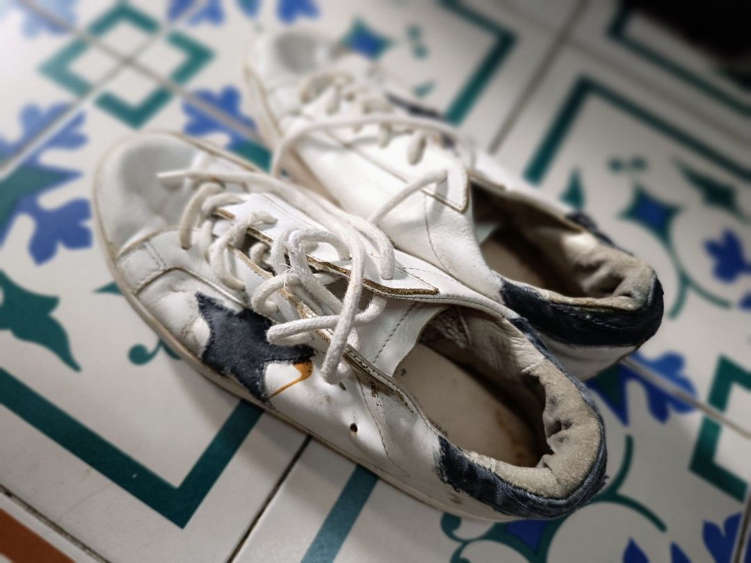 Golden Goose White Leather Sneakers (Category: Sneakers) located in Manila. Submitted by wheng08 (Listing ID 1442220659, Image 1). Description: - Classic white leather sneakers - Black star detail on the side - Visible scuffs and dirt marks on soles and uppers from box , selling as is - White laces - Interior lining shows some wear - Ideal for everyday wear.