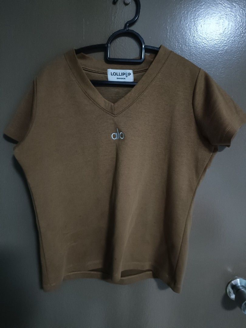 Lollipop V-neck T-shirt with Alo Logo (Category: Other Tops) located in Singapore. Submitted by plantar59 (Listing ID 1442264207, Image 1). Description: - Brand: Lollipop - Color: Brown - Neckline: V-neck - Features: Alo logo on chest - Sleeves: Short sleeves - Style: Comfortable everyday top, good for casual wear -ptp 50.