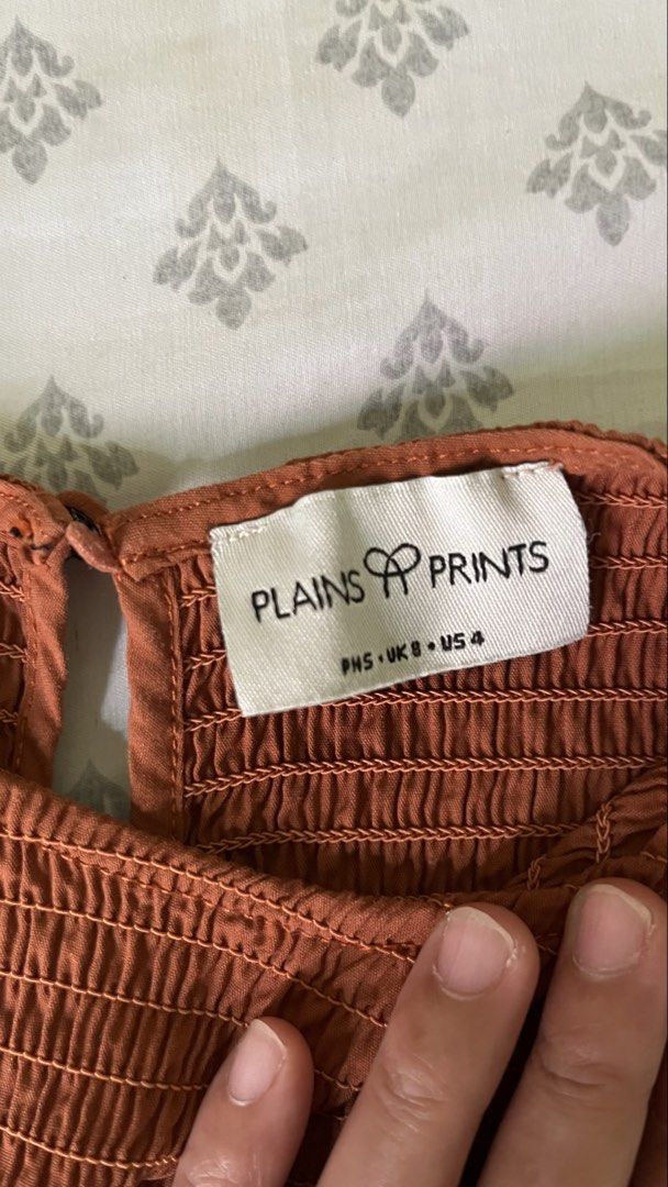 Plains & Prints Smocked Peplum Top (Category: Sleeveless) located in Pasig City. Submitted by khimlats (Listing ID 1442175984, Image 2). Description: - Rust colored smocked top - Brand: Plains & Prints - Sleeveless design - Peplum hem - Button closure at the back neck - Comfortable and stylish - Versatile for casual or dressed-up occasions -Used 4x.