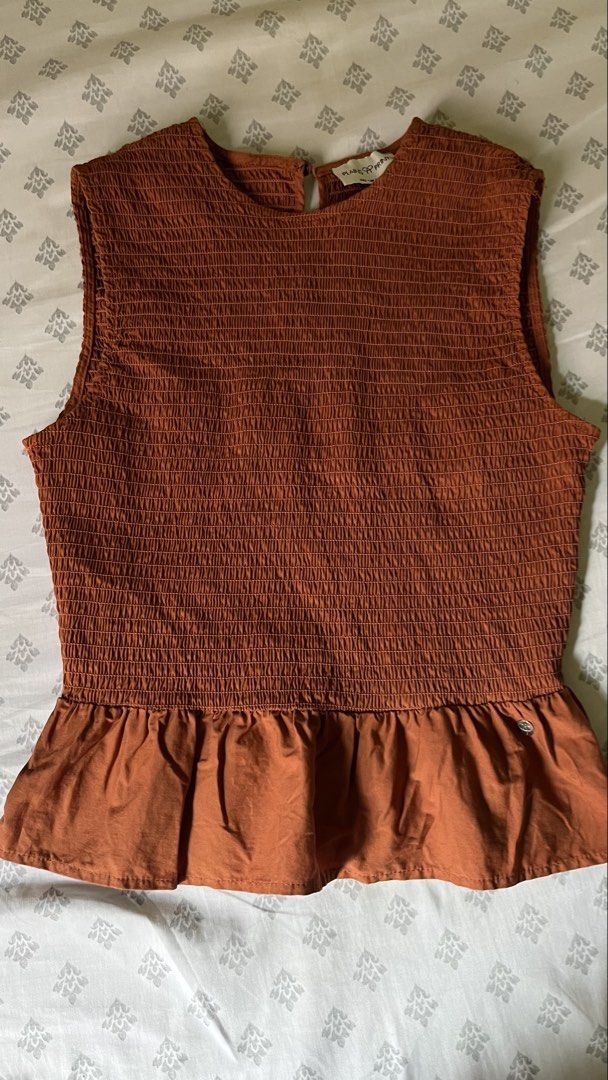 Plains & Prints Smocked Peplum Top (Category: Sleeveless) located in Pasig City. Submitted by khimlats (Listing ID 1442175984, Image 1). Description: - Rust colored smocked top - Brand: Plains & Prints - Sleeveless design - Peplum hem - Button closure at the back neck - Comfortable and stylish - Versatile for casual or dressed-up occasions -Used 4x.