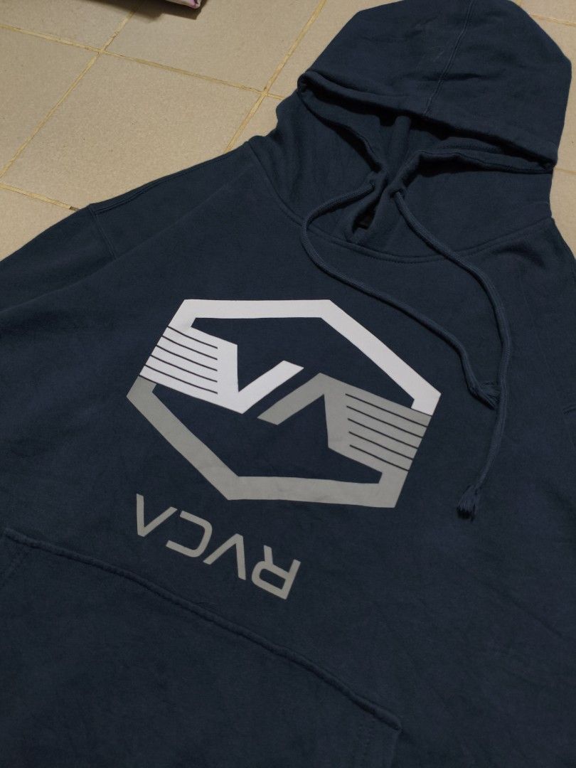 RVCA Navy Blue Graphic Hoodie (Category: Hoodies) located in Bayambang. Submitted by rajuergui76226 (Listing ID 1442332883, Image 2). Description: RVCA hoodie in navy blue. Features a large graphic logo on the front. Has a front pocket and drawstring hood. Tag says Large-XL. Measurements are 25x28. Excellent condition, color is a 9.5/10..