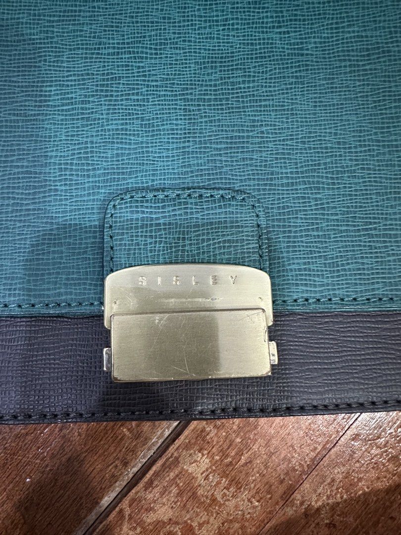 Sisley Shoulder Bag - Teal and Dark Grey (Category: Shoulder Bags) located in Del Monte. Submitted by bittersweetcigs (Listing ID 1442279962, Image 2). Description: - Stylish teal and dark grey shoulder bag - Textured material for a unique look - Secure gold-tone buckle closure with 'Sisley' logo - Adjustable strap for comfortable carrying - Ideal for everyday use.