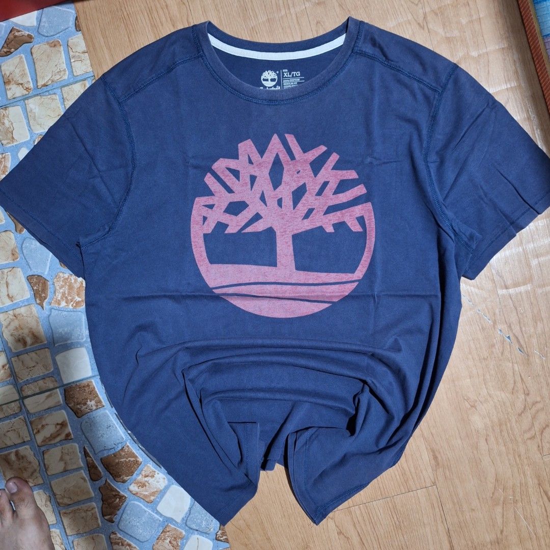 Timberland Big Logo (Category: Tshirts & Polo Shirts ) located in Aroroy. Submitted by rewear_r3volution (Listing ID 1442330139, Image 1). Description: This is a navy blue Timberland t-shirt featuring a prominent red tree logo on the chest. Size XL.