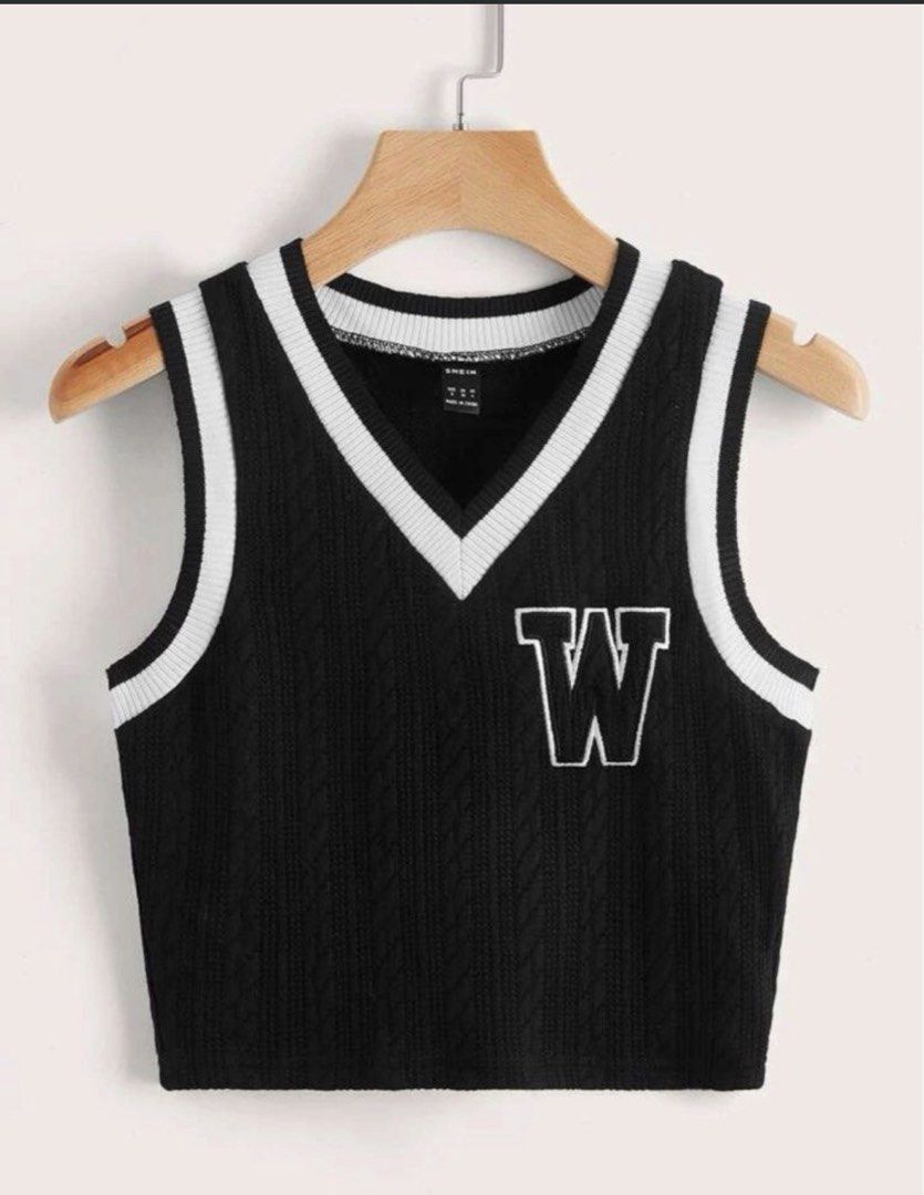 SHEIN Knit Vest (Category: Blouses) located in Cainta. Submitted by gingercatluca (Listing ID 1442406692, Image 1). Description: - Black knitted vest with classic cable knit pattern. - Features a white embroidered 'W' patch on the front. - Ribbed trim with white stripes on V-neck and armholes. - Trendy cropped length. - Versatile for layering over shirts or wearing solo..