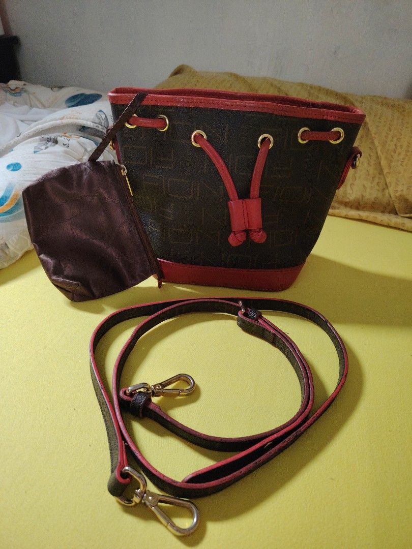 Brown Monogram Bucket Bag with Red Trim and Pouch (Category: Cross-body Bags) located in Taguig. Submitted by roxie0419 (Listing ID 1442344573, Image 1). Description: - Stylish brown bucket bag with repeating monogram pattern - Elegant red leather trim and drawstring details - Includes a small matching pouch for essentials - Detachable crossbody strap for versatile carrying - Polished gold hardware accents - Interior branded tag for authenticity 
