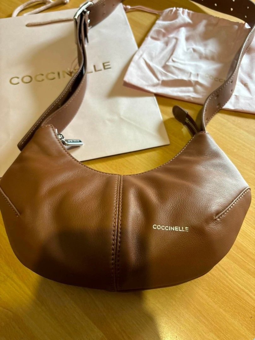 Coccinelle Leather Hobo Bag Brown (Category: Luxury Bags & Wallets) located in Manila. Submitted by hannauhfinds (Listing ID 1442462985, Image 2). Description: - Genuine brown leather hobo bag by Coccinelle - Soft, supple leather with a stylish curved shape - Adjustable strap with a chic buckle detail - Interior includes a secure zipped pocket and card slots - Comes with original dust bag and shopping bag - Ideal for everyday wear and versatile s