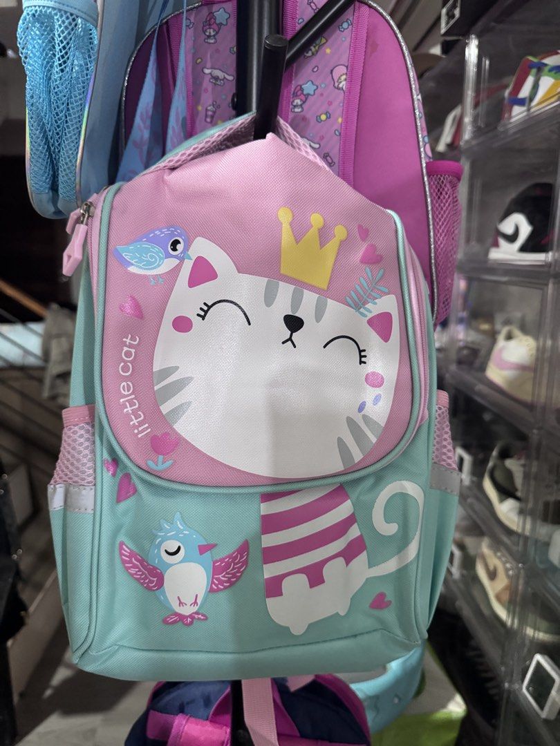 Cute Little Cat & Bird Backpack for Kids (Category: Babies & Kids Fashion) located in Carmona. Submitted by eraest (Listing ID 1442497570, Image 1). Description: - Adorable kids backpack featuring a cute cat with a crown and a bird. - Stylish striped scarf detail. - Lovely light blue and pink color combination. - Convenient side mesh pockets for water bottles. - Ideal for school, daycare, or fun outings..