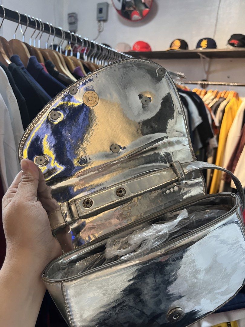 Diesel Silver Metallic Shoulder Bag (Category: Shoulder Bags) located in Davao. Submitted by 4mscllection (Listing ID 1442406411, Image 2). Description: - Cool silver shoulder bag from Diesel - Shiny metallic finish - Signature Diesel logo on the front - Interior zip pocket and main compartment - Magnetic snap closure - Perfect statement piece.