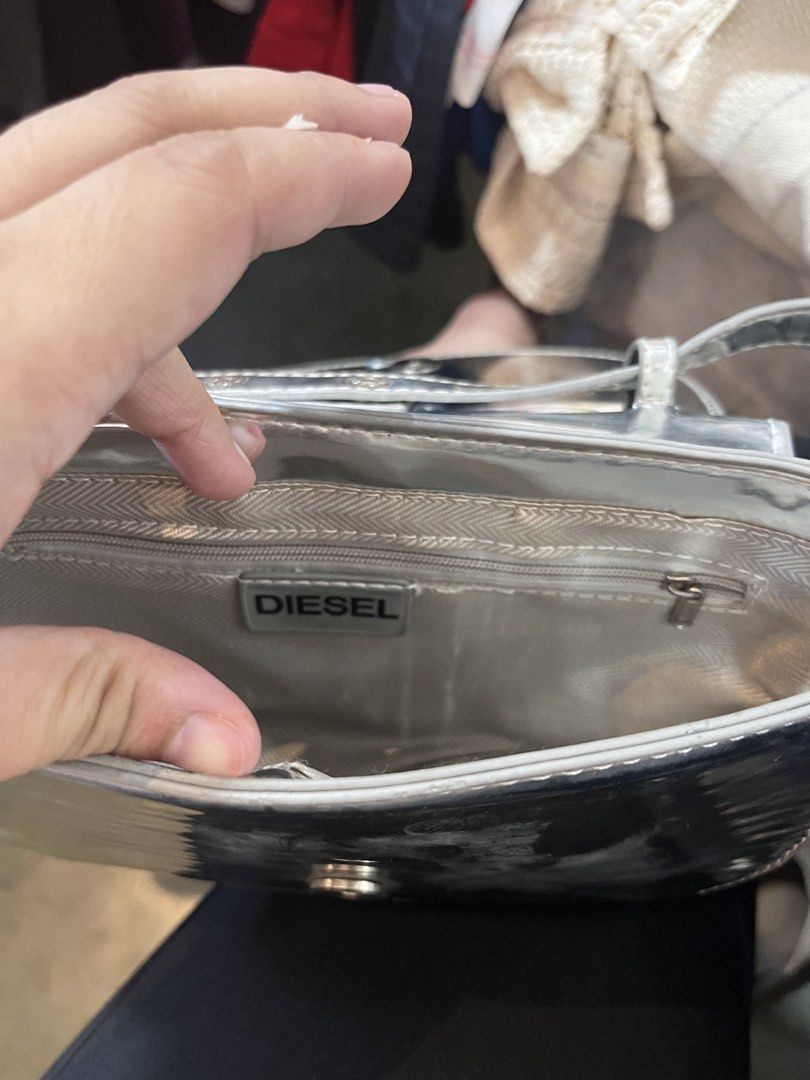 Diesel Silver Metallic Shoulder Bag (Category: Shoulder Bags) located in Davao. Submitted by 4mscllection (Listing ID 1442406411, Image 3). Description: - Cool silver shoulder bag from Diesel - Shiny metallic finish - Signature Diesel logo on the front - Interior zip pocket and main compartment - Magnetic snap closure - Perfect statement piece.