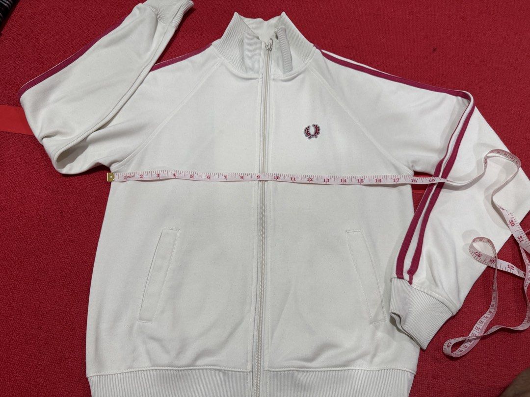 Fred Perry White Track Jacket with Burgundy Stripes (Category: Coats, Jackets and Outerwear) located in Manila. Submitted by pormaatbpshoppe (Listing ID 1442362428, Image 2). Description: - White Fred Perry track jacket - Iconic embroidered laurel wreath logo on chest - Burgundy stripes along sleeves and collar - Full zip closure - Two side pockets - Ribbed cuffs and hem.