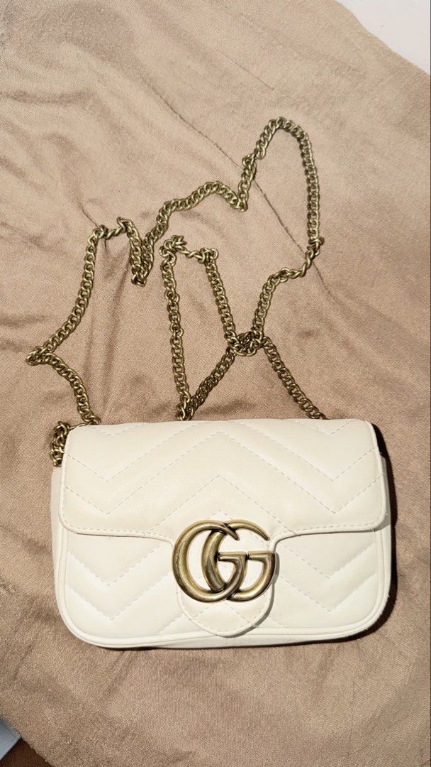 Gucci GG Super Mini Marmont Sling bag (Category: Luxury Bags & Wallets) located in San Pablo. Submitted by dees_collection (Listing ID 1442515574, Image 2). Description: Material: Supple white matelassé chevron leather with a stitched heart detail on the back. Hardware: Antique, brushed gold-toned Double G logo on the front flap. Strap: Detachable chain shoulder strap that can also be looped to wear the bag as a belt or attached to a larger bag. 