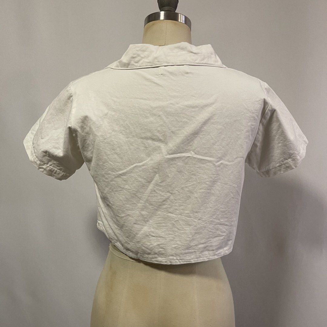 Nanny White Cropped Button-Up Shirt with Pockets (Category: Shirts) located in General Trias. Submitted by 1992thelabel (Listing ID 1442466647, Image 2). Description: - White cropped shirt from Nanny - Short sleeves - Collared neckline - Two chest pockets with button closures - Button-up front - Made in Thailand - Versatile piece, pairs well with high-waisted bottoms.