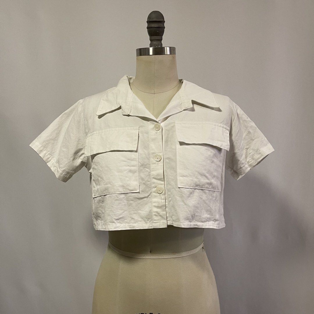 Nanny White Cropped Button-Up Shirt with Pockets (Category: Shirts) located in General Trias. Submitted by 1992thelabel (Listing ID 1442466647, Image 1). Description: - White cropped shirt from Nanny - Short sleeves - Collared neckline - Two chest pockets with button closures - Button-up front - Made in Thailand - Versatile piece, pairs well with high-waisted bottoms.