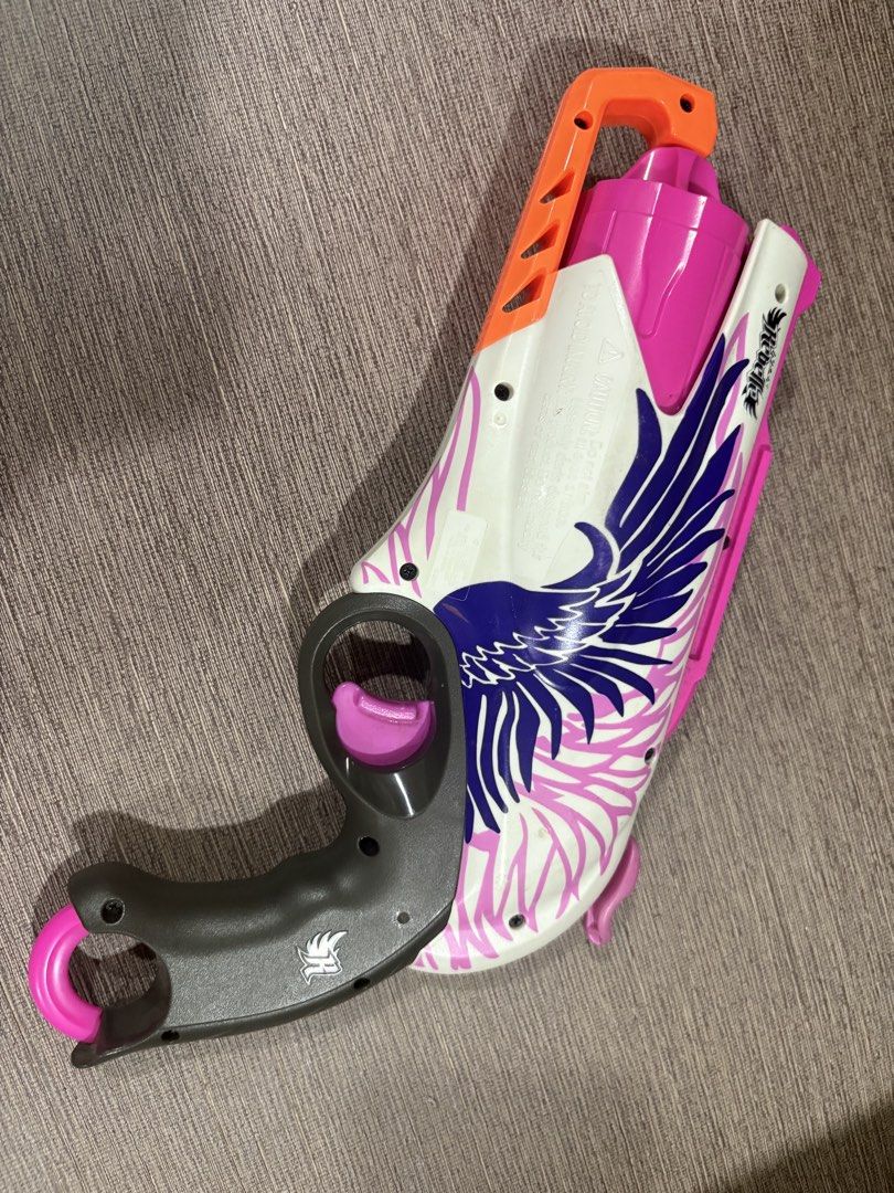 Nerf Rebelle Sweet Revenge blaster (Category: Cases & Sleeves) located in Manila. Submitted by dig76 (Listing ID 1442442677, Image 3). Description: This is a Hasbro Nerf Rebelle Sweet Revenge blaster, featuring a white and pink design with purple wing graphics and a 5-dart revolving barrel. The blaster is designed for hammer-action firing and can reach distances of up to 75 feet..