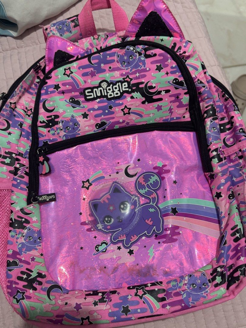 Smiggle Backpack Cat Space Theme Pink Purple (Category: Babies & Kids Fashion) located in Manila. Submitted by mitchvi88823135 (Listing ID 1442359161, Image 2). Description: - Adorable Smiggle backpack with a fun cat in space design. - Features stars and planets in vibrant pink and purple colors. - Includes a spacious main compartment and a convenient front zip pocket. - Padded shoulder straps ensure comfortable wear. - Ideal for school, daycare,