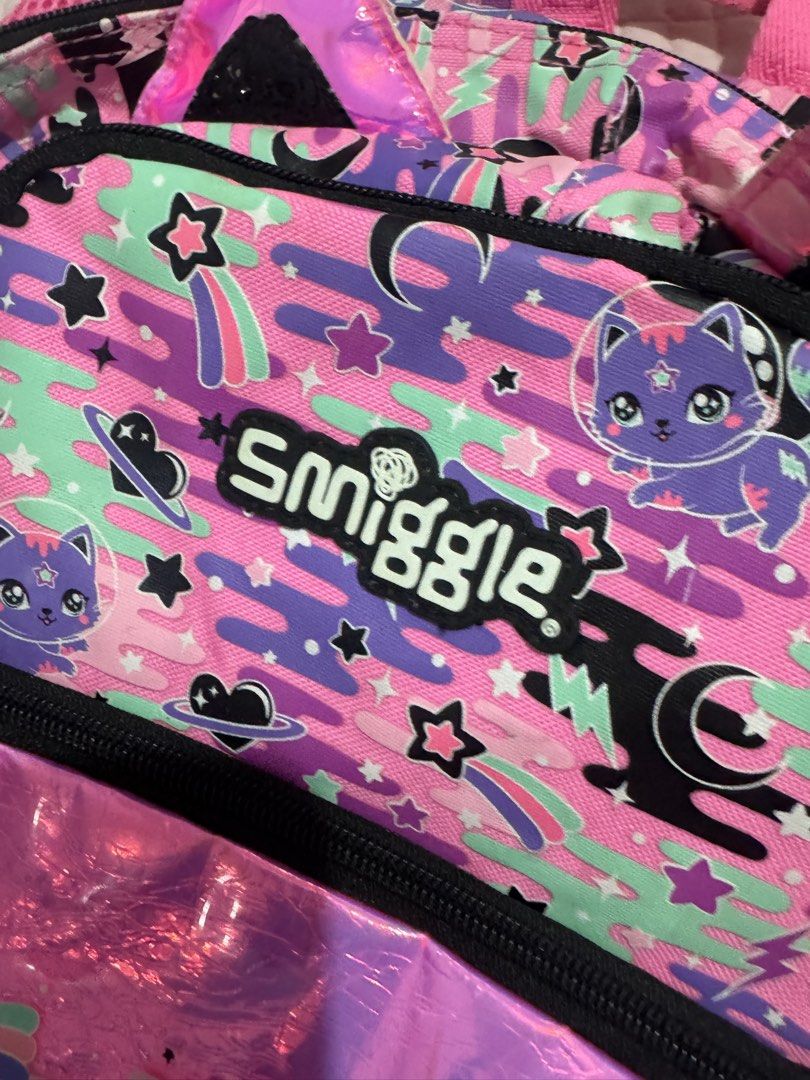 Smiggle Backpack Cat Space Theme Pink Purple (Category: Babies & Kids Fashion) located in Manila. Submitted by mitchvi88823135 (Listing ID 1442359161, Image 1). Description: - Adorable Smiggle backpack with a fun cat in space design. - Features stars and planets in vibrant pink and purple colors. - Includes a spacious main compartment and a convenient front zip pocket. - Padded shoulder straps ensure comfortable wear. - Ideal for school, daycare,
