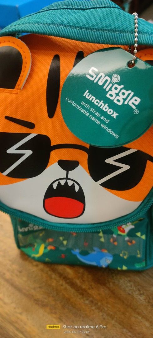 Smiggle Tiger Lunchbox with Strap and Name Windows (Category: Food Organization & Storage) located in Paranaque City. Submitted by kng_preloved (Listing ID 1442516539, Image 1). Description: - Awesome Smiggle lunchbox featuring a cool tiger design with sunglasses and a fun expression. - Comes with a detachable strap for easy carrying. - Includes letter tiles to personalize the name windows. - Ideal for school lunches or fun day trips. - Features 
