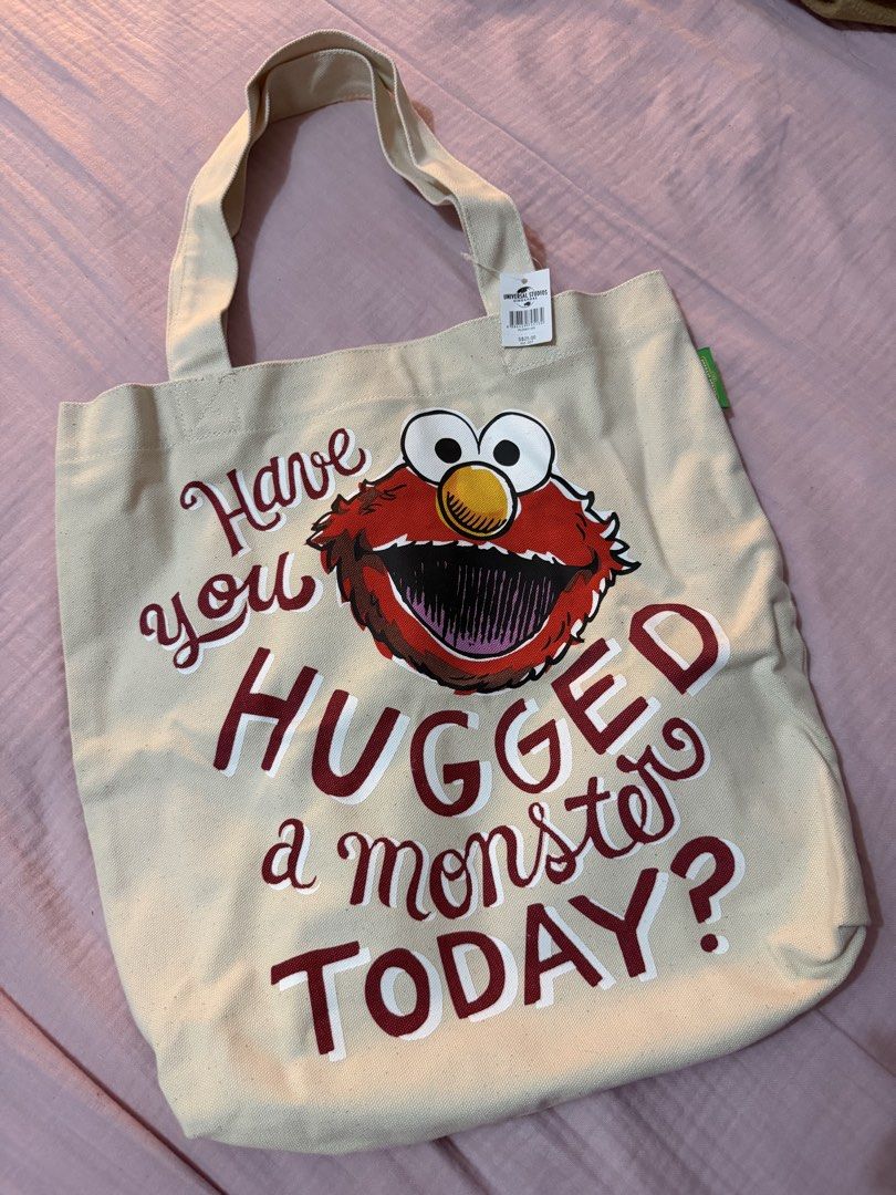 Universal Studios Singapore Elmo Tote Bag (Category: Tote Bags) located in Manila. Submitted by deklutterph (Listing ID 1442479470, Image 1). Description: - Adorable Elmo graphic canvas tote bag - Features the fun quote: 'Have you HUGGED a monster TODAY?' - Authentic purchase from Universal Studios Singapore - Original tag included, showing purchase price of S$25.00 - Great for Sesame Street fans and everyday use!.