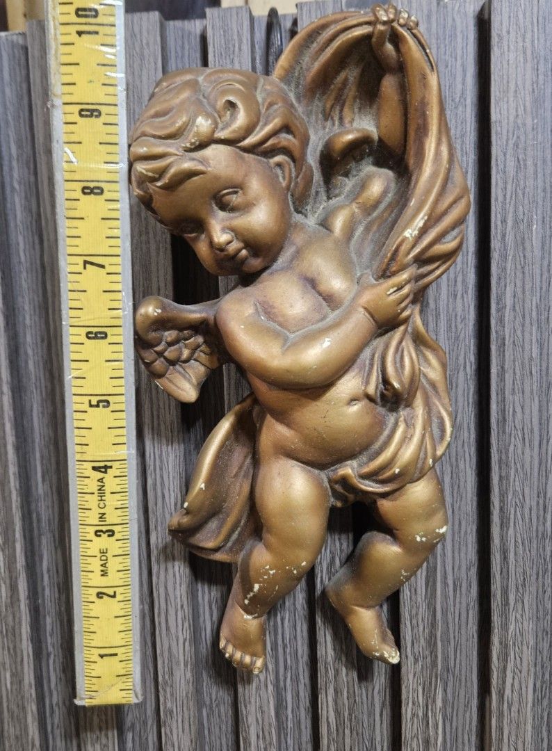 Vintage Gold Cherub Angel Wall Hanging Decor (Category: Wall Decor) located in Rizal. Submitted by cherry_garcia (Listing ID 1442421621, Image 2). Description: - Adorable cherub angel wall hanging - Elegant gold-tone finish - Stands approximately 9 inches tall - Features minor paint chips, consistent with vintage charm - Adds a touch of vintage charm to any space - Ideal for nurseries, living rooms, or any room needing a sweet accent.