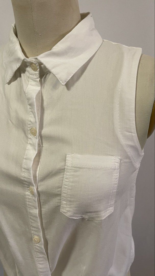 White Sleeveless Button-Up Shirt with Tie Front (Category: Blouses) located in General Trias. Submitted by 1992thelabel (Listing ID 1442466628, Image 2). Description: - Classic white sleeveless shirt - Button-up front with a left chest pocket - Unique knot detail at the bottom - Collared shirt style - Versatile and easy to pair with any outfit - Ideal for warm weather.
