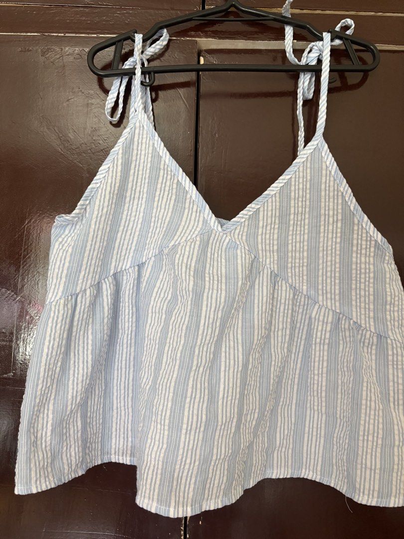 Blue and White Striped Tie-Strap Summer Top (Category: Sleeveless) located in Manila. Submitted by secondsbyem (Listing ID 1442594460, Image 2). Description: - Cute blue and white striped peplum top - Adjustable tie straps on shoulders - Flattering V-neckline - Empire waist design - Lightweight fabric, ideal for warm weather - Versatile: pairs well with shorts or jeans - Perfect for casual outings and beach days.