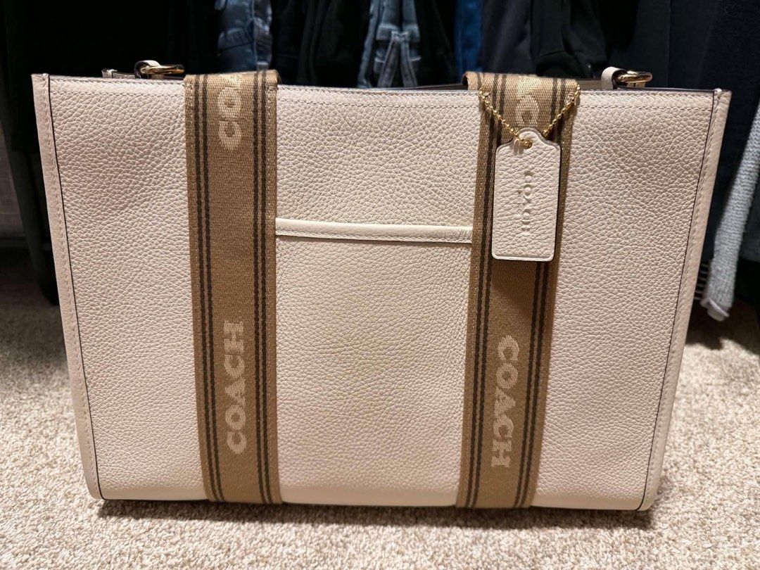 Coach Smith Tote Bag with Signature Strap (Category: Tote Bags) located in Antipolo. Submitted by jarazote (Listing ID 1442569408, Image 1). Description: - Authentic Coach tote bag - Elegant light neutral color pebbled - Signature Coach logo strap detail - Comfortable top handles - Interior zip pocket for essentials - Comes with original Coach hangtag - Ideal for everyday use and travel - price negotiable.