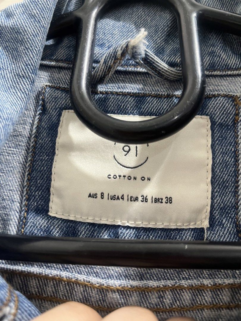 Cotton On Blue Denim Jacket Distressed Details (Category: Coats, Jackets and Outerwear) located in Cagayan de Oro. Submitted by everythingpreloved__ (Listing ID 1442685893, Image 3). Description: - Classic blue denim jacket from Cotton On - Distressed look with rips on front and back - Button-up closure - Two chest pockets - Buttoned cuffs - Ideal for casual layering and styling.