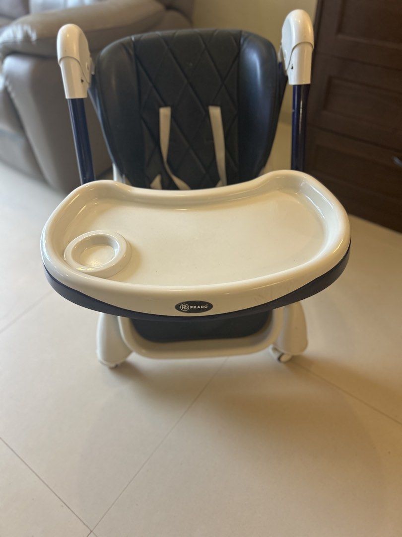 Foldable Baby High Chair with Tray (Category: Baby High Chairs) located in Singapore. Submitted by srinidhi247 (Listing ID 1442677180, Image 3). Description: - Dark blue padded seat - White tray with cup holder - White and blue frame - Wheels for easy movement - Folds for convenient storage.