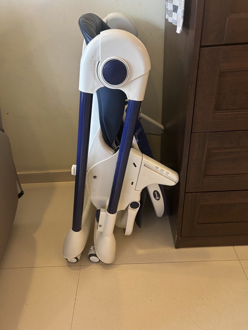 Foldable Baby High Chair with Tray (Category: Baby High Chairs) located in Singapore. Submitted by srinidhi247 (Listing ID 1442677180, Image 2). Description: - Dark blue padded seat - White tray with cup holder - White and blue frame - Wheels for easy movement - Folds for convenient storage.