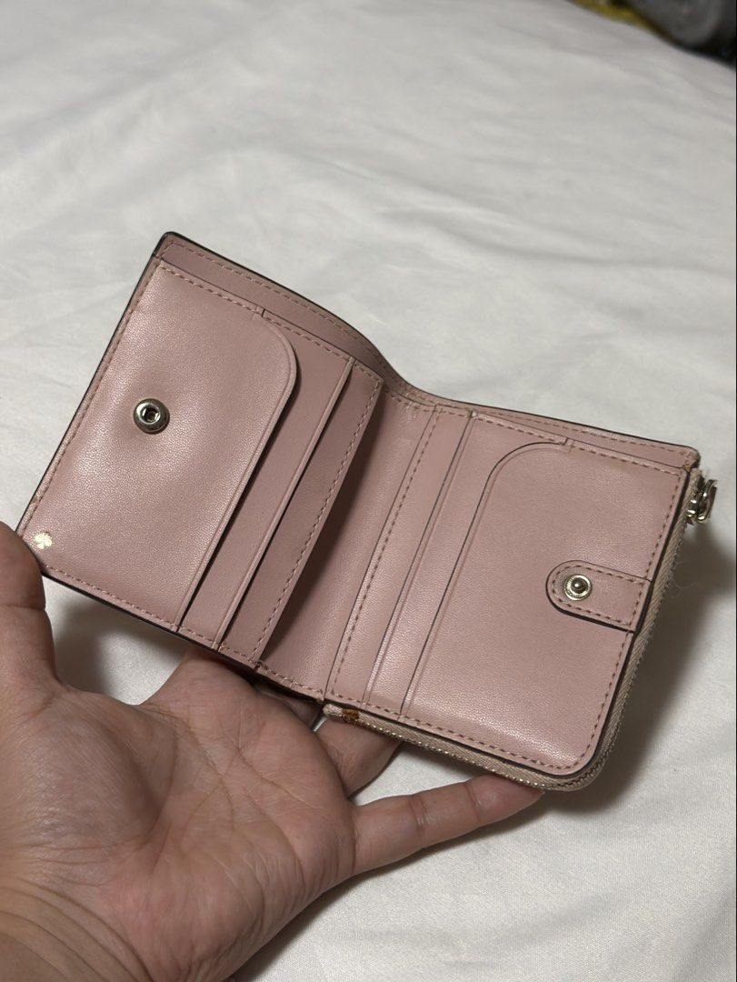 Kate Spade Pink Leather Bifold Wallet (Category: Wallets & Card holders) located in Muntinlupa City. Submitted by kiarraaa (Listing ID 1442545615, Image 2). Description: - Brand: Kate Spade - Color: Pink - Material: Leather - Style: Bifold Wallet - Features: Zip around coin pocket, interior card slots, snap closure for bills - Exterior: Small logo on the front - Approximate Dimensions (closed): 4.5 inches wide x 3.5 inches tall .