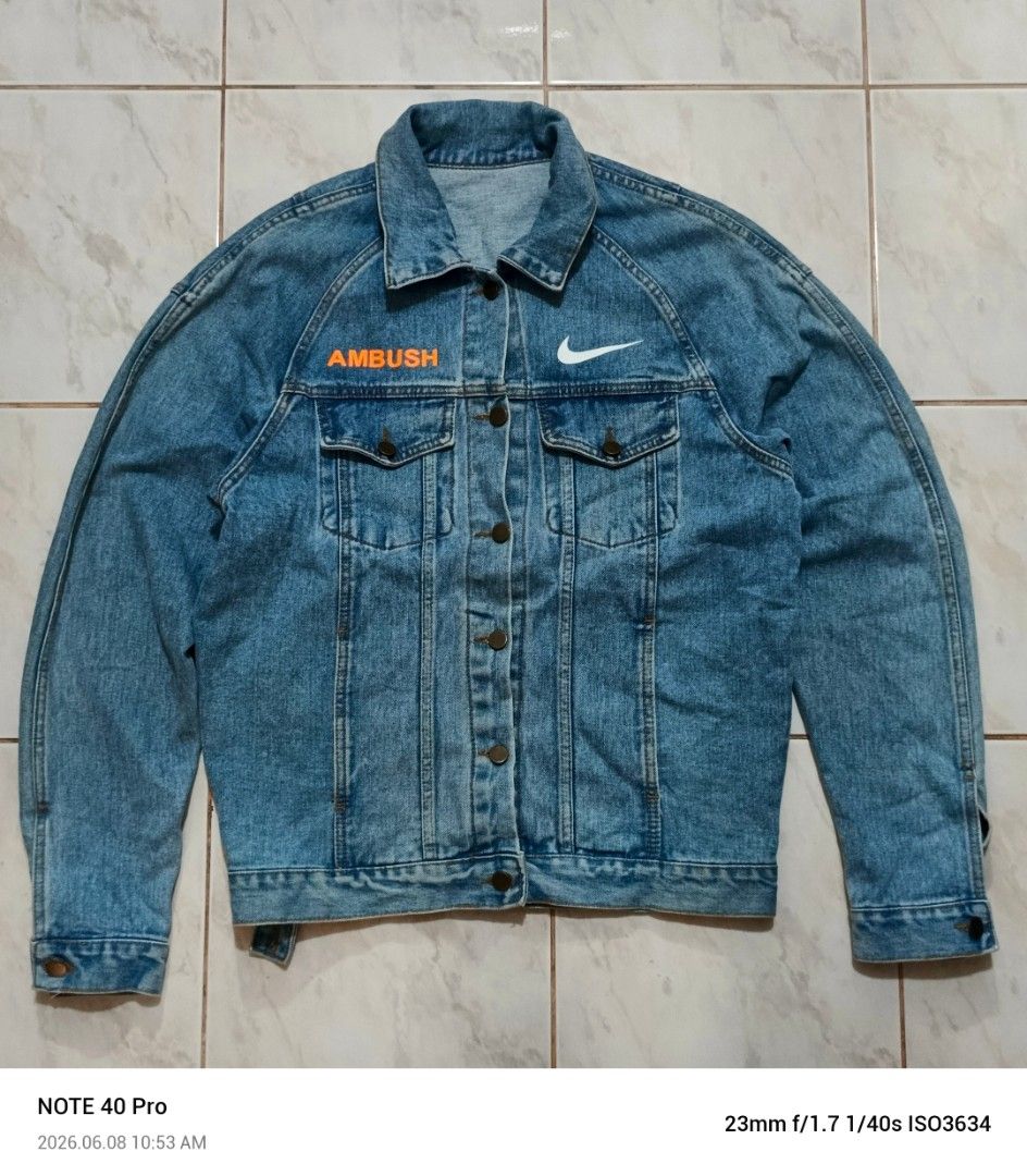 Nike x Ambush Denim Jacket (Category: Coats, Jackets and Outerwear) located in Manila. Submitted by jeffies4ti96921 (Listing ID 1442587607, Image 2). Description: - Authentic Nike x Ambush collaboration denim jacket. - Iconic Nike swoosh detail on the front. - Bold, large Nike logo prominently displayed on the back. - 'Ambush' text branding on the chest. - Classic denim jacket design with button closure. - Functional pockets for convenience. - A 