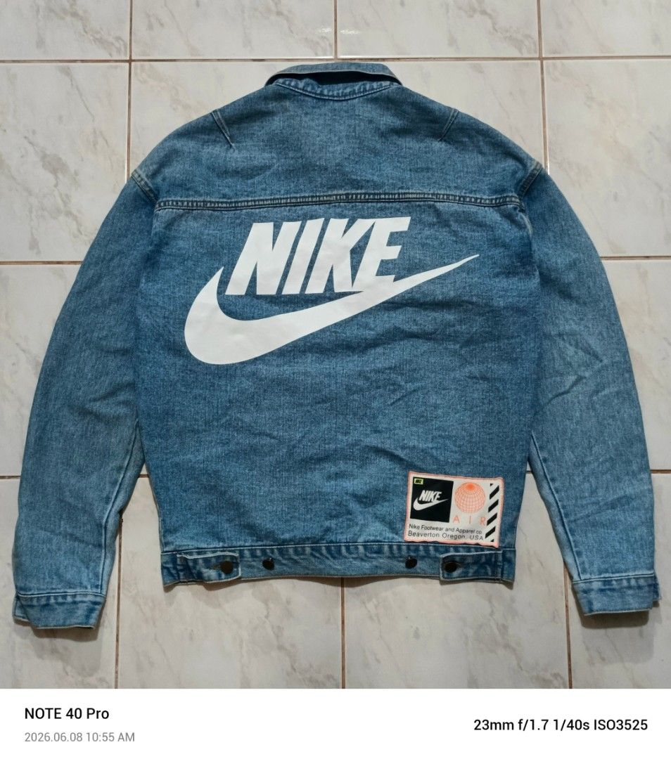 Nike x Ambush Denim Jacket (Category: Coats, Jackets and Outerwear) located in Manila. Submitted by jeffies4ti96921 (Listing ID 1442587607, Image 1). Description: - Authentic Nike x Ambush collaboration denim jacket. - Iconic Nike swoosh detail on the front. - Bold, large Nike logo prominently displayed on the back. - 'Ambush' text branding on the chest. - Classic denim jacket design with button closure. - Functional pockets for convenience. - A 