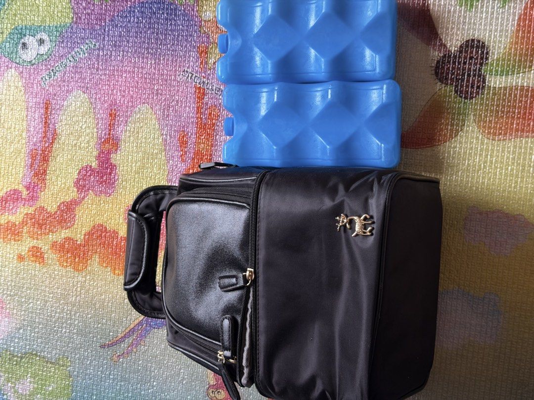 Black Cooler Bag with 2 Blue Ice Packs (Category: Breastfeeding & Bottle Feeding) located in Mabalacat. Submitted by ladybugxx (Listing ID 1442759043, Image 2). Description: - Black cooler bag - Vcool brand - Includes 2 blue reusable wavy ice packs - Keeps food and drinks cold - Features a main compartment and a front pocket - Zippers are in good working condition - Perfect for breastmilk, picnics, travel, and everyday use.