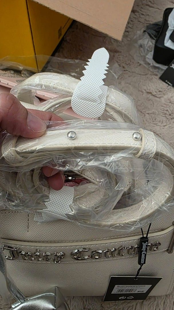 Juicy Couture Cream Handbag with Silver Pouch (Category: Purses & Pouches) located in San Leonardo. Submitted by arni0179 (Listing ID 1442882626, Image 3). Description: - Cream-colored Juicy Couture handbag - Includes matching silver pouch attached - Prominent Juicy Couture logo on the front - Protective metal feet on the bottom - Brand new with tags still attached - Versatile for everyday use or evening events.