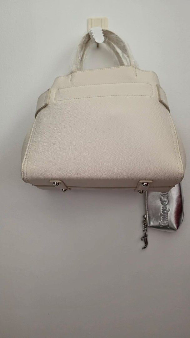 Juicy Couture Cream Handbag with Silver Pouch (Category: Purses & Pouches) located in San Leonardo. Submitted by arni0179 (Listing ID 1442882626, Image 2). Description: - Cream-colored Juicy Couture handbag - Includes matching silver pouch attached - Prominent Juicy Couture logo on the front - Protective metal feet on the bottom - Brand new with tags still attached - Versatile for everyday use or evening events.