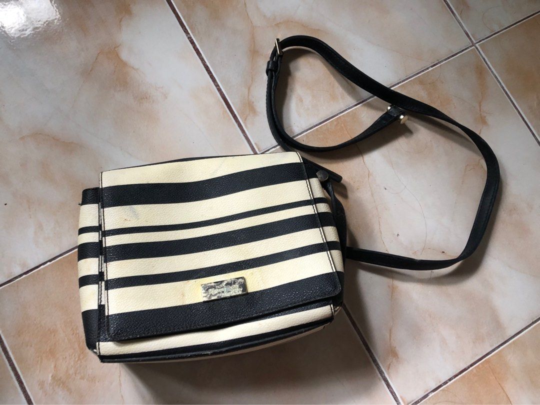 (Kate Spade) Striped Crossbody Bag (Category: Cross-body Bags) located in Mapandan. Submitted by olibski (Listing ID 1442782356, Image 1). Description: Heavily Used, Strap has been detached. - Authentic Kate Spade crossbody bag - Classic black and cream stripe design - Durable leather and PVC material - Interior features signature Kate Spade logo lining - Adjustable strap for comfortable wear - Shows some signs of wear on the metal plate and bag,